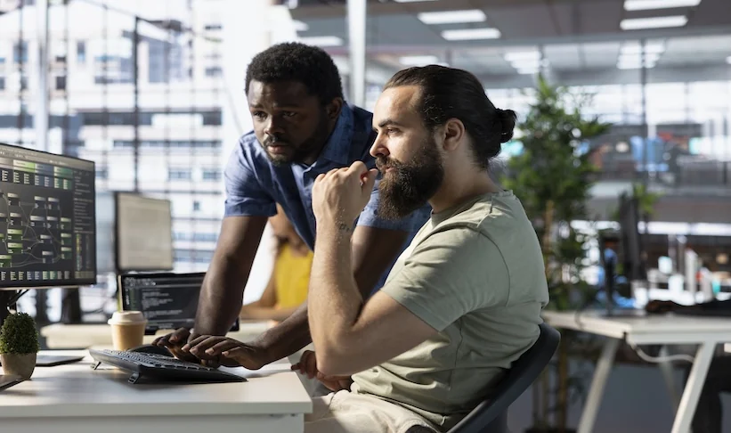 Twee collega's bekijken samen informatie op een computerscherm